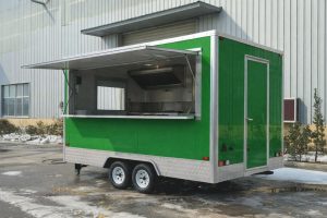 Een moderne groene foodtruck met open verkoopklep op een industrieterrein.