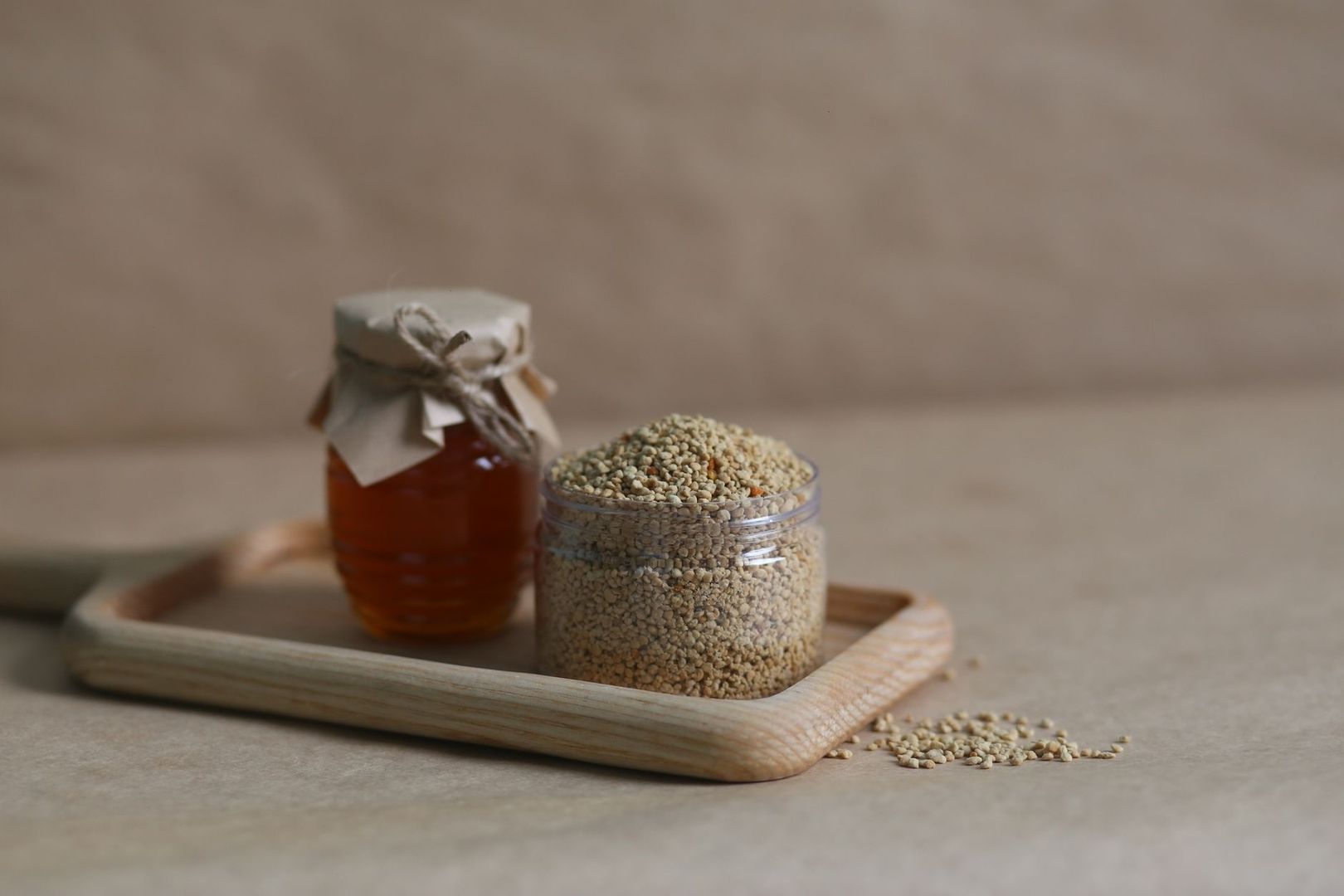 Pot met kleine granen naast een pot amberkleurige vloeistof op een houten schaal